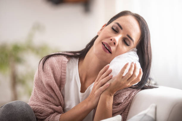 Patient resting with ice pack after dental implant surgery at home